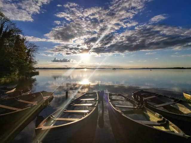 Boats moored on the shore of Lough Owel with open water and far shore beyond.
