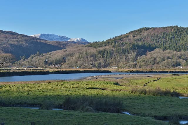 The Mawddach above Penmaenpool in winter light, a wide flat glide with wooded valley sides rising steeply.