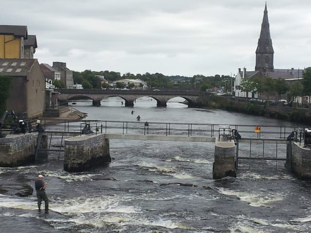 An angler fly fishing on the River Moy at Ballina with the cathedral behind.