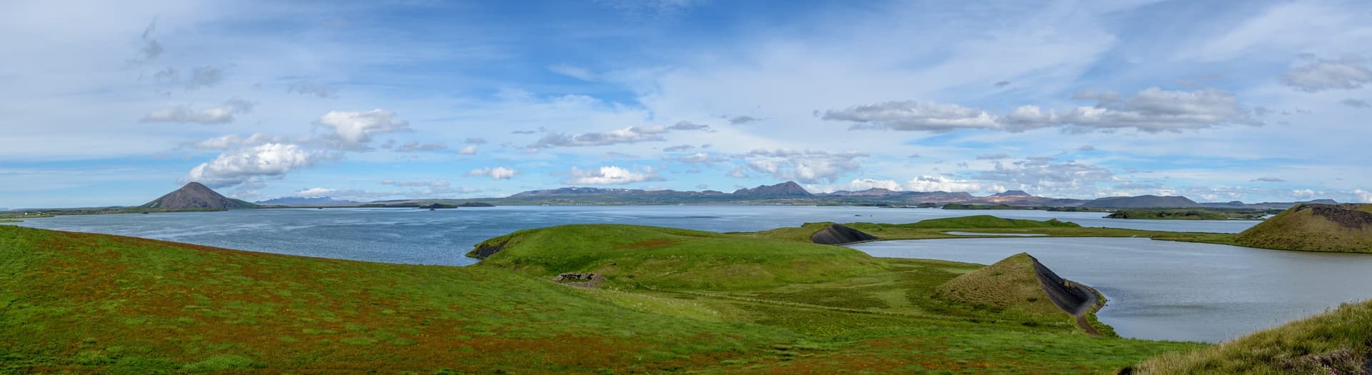 Wide panorama of Lake Mývatn, the calm open water surface with volcanic hills and lava fields beyond.