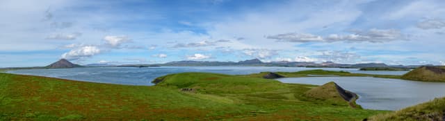 Wide panorama of Lake Mývatn, the calm open water surface with volcanic hills and lava fields beyond.