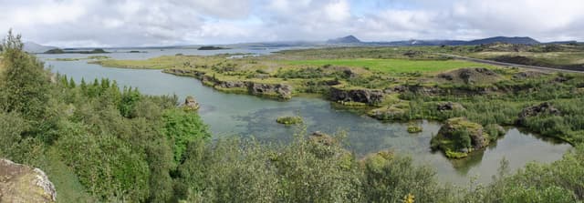 Broad panorama across the open water of Lake Mývatn with lava fields and mountains.