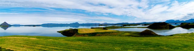 Panoramic view of Lake Mývatn, the calm reflective water surface and surrounding volcanic hills.