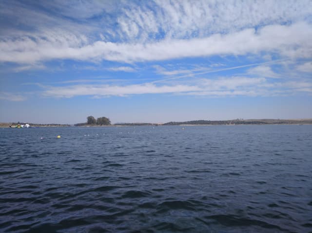 Shore-level view of Embalse de Orellana showing the calm reservoir surface in summer.