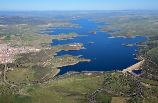 Wide view of the Orellana La Vieja reservoir and dam, open water stretching across the Extremaduran plain.