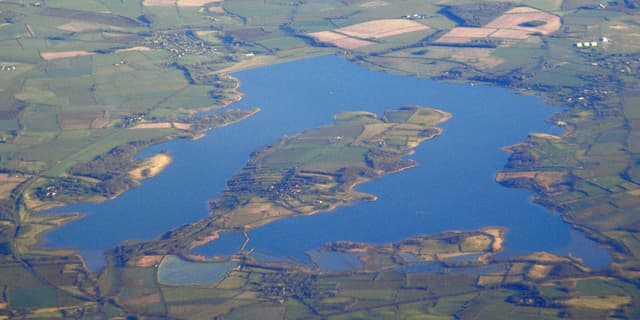 Aerial photograph over the full extent of Rutland Water reservoir with both bays visible.