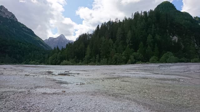 The Sava Dolinka flowing alongside Lake Jasna near Kranjska Gora, the Julian Alps reflected in clear water.