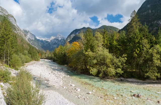 The Soča river winding through the Trenta valley with Julian Alps peaks behind.