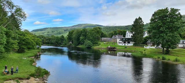 Panoramic view of the River Tay at Kenmore where it exits Loch Tay, with the village and hills beyond.