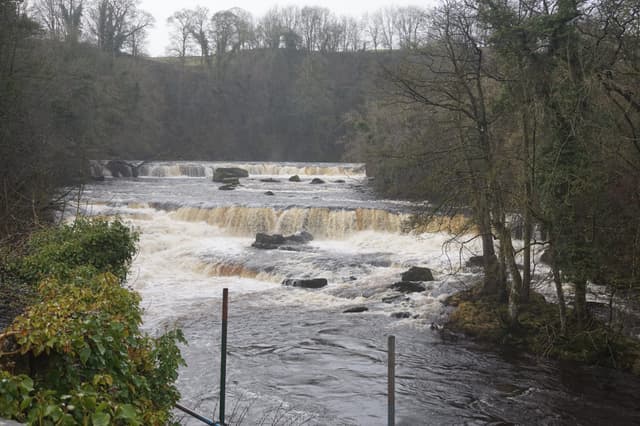 The River Ure cascading over the broad limestone shelves of Aysgarth Falls in winter light.